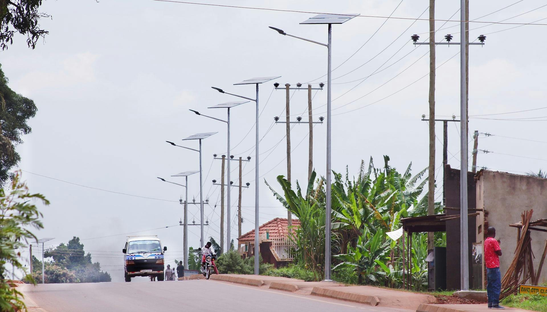A road where a series of utility poles with solar panels are mounted.