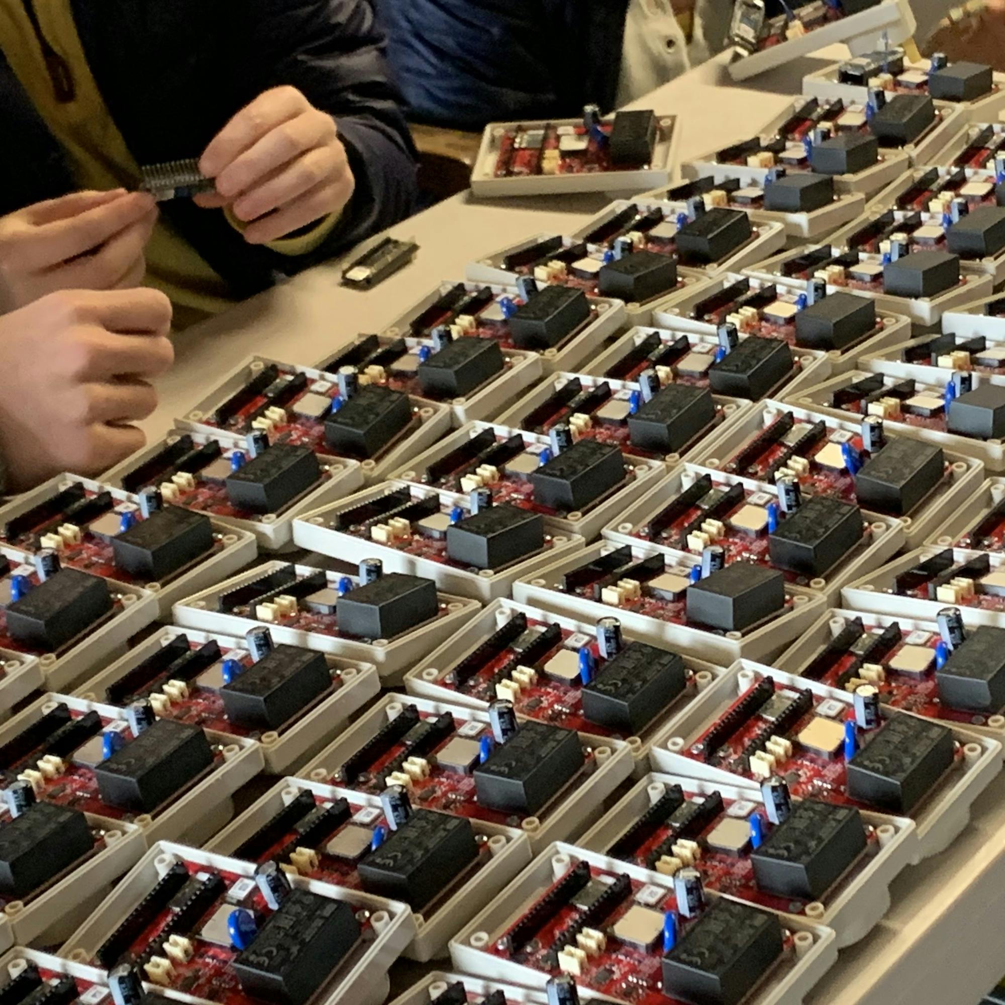 PowerWatch sensors being assembled on a table with the circuit-board exposed.